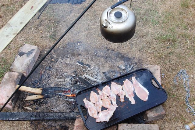 Bacon cooking on a campfire at Dernwood Farm campsite in East Sussex