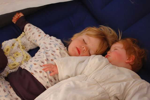 Two babies in pyjamas and wearable sleeping bag camping