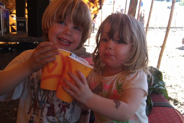 Two children doing cheers with their drinks at Glastonbury Festival