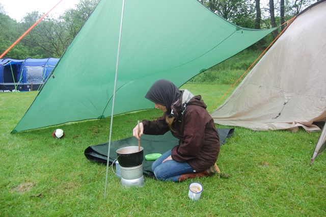 Cath cooking with midge buff under a tarp